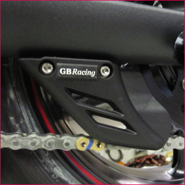 Close-up of a motorcycle chain guard with 'GBRacing' branding.