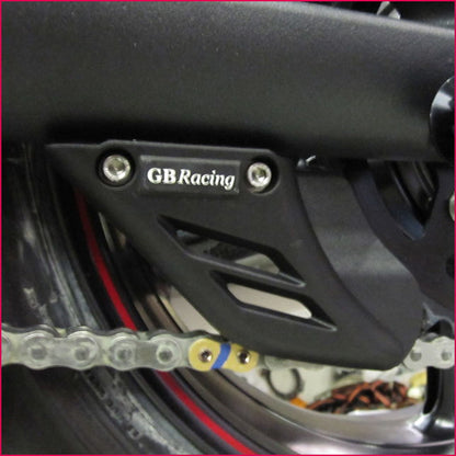Close-up of a motorcycle chain guard with 'GBRacing' branding.