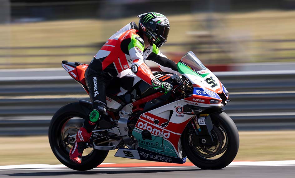 Motorcycle racer in action on a track with sponsor logos.